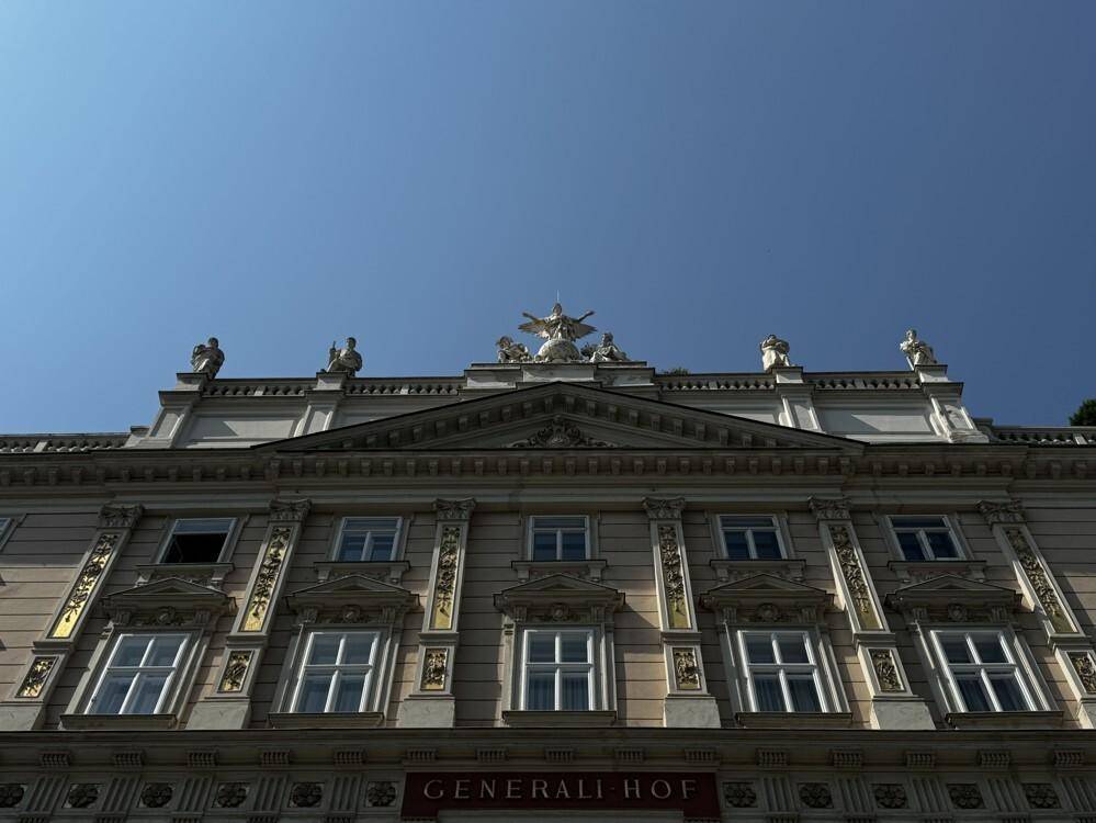 Detailaufnahme des oberen Teils der historischen Fassade mit Skulpturen und architektonischen Verzierungen.