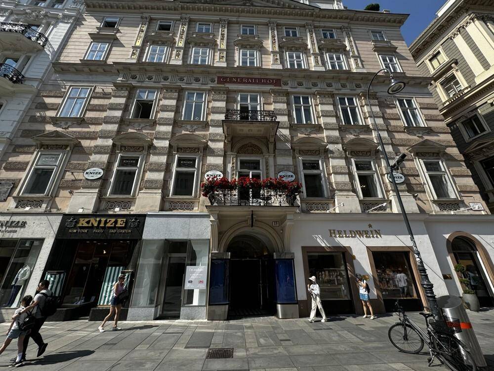 Ansicht der historischen Gebäudefassade mit detaillierten Verzierungen und Geschäften im Erdgeschoss.