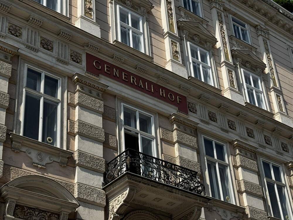 Nahaufnahme der historischen Fassade mit verzierten Fenstern und einem schmiedeeisernen Balkon.