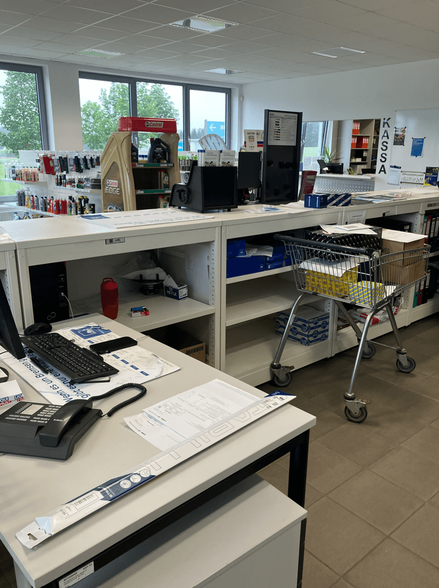 Arbeitsbereich mit Schreibtischen, Computern und Regalen, die Produkte und Büromaterialien für den Verkauf bereithalten.