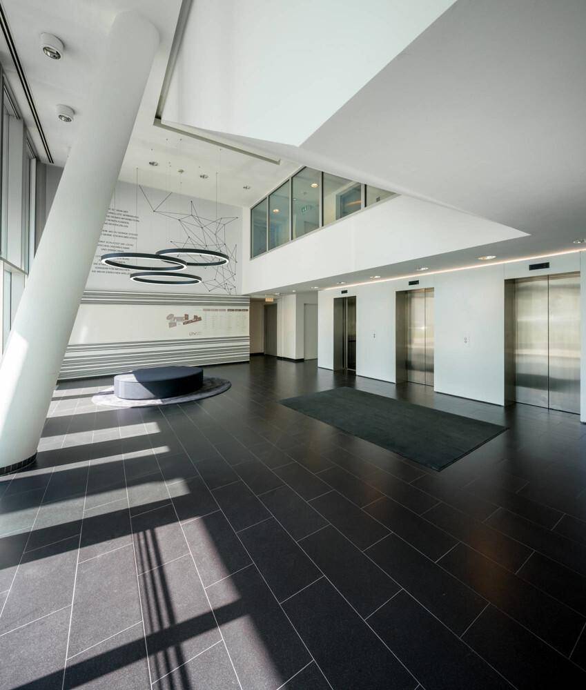 Helle und moderne Lobby mit Aufzügen, dunklem Fliesenboden und minimalistischer Dekoration.