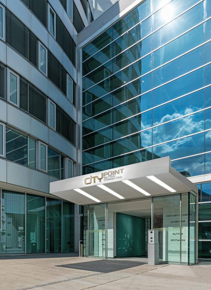 Hauptzugang eines modernen Bürokomplexes mit Glasfassade und dem Schriftzug "CITY POINT".