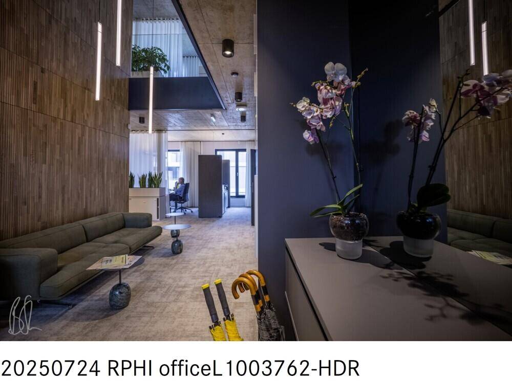 Moderner Büroeingangsbereich mit Sitzgelegenheiten, Holzwänden und dekorativen Pflanzen.