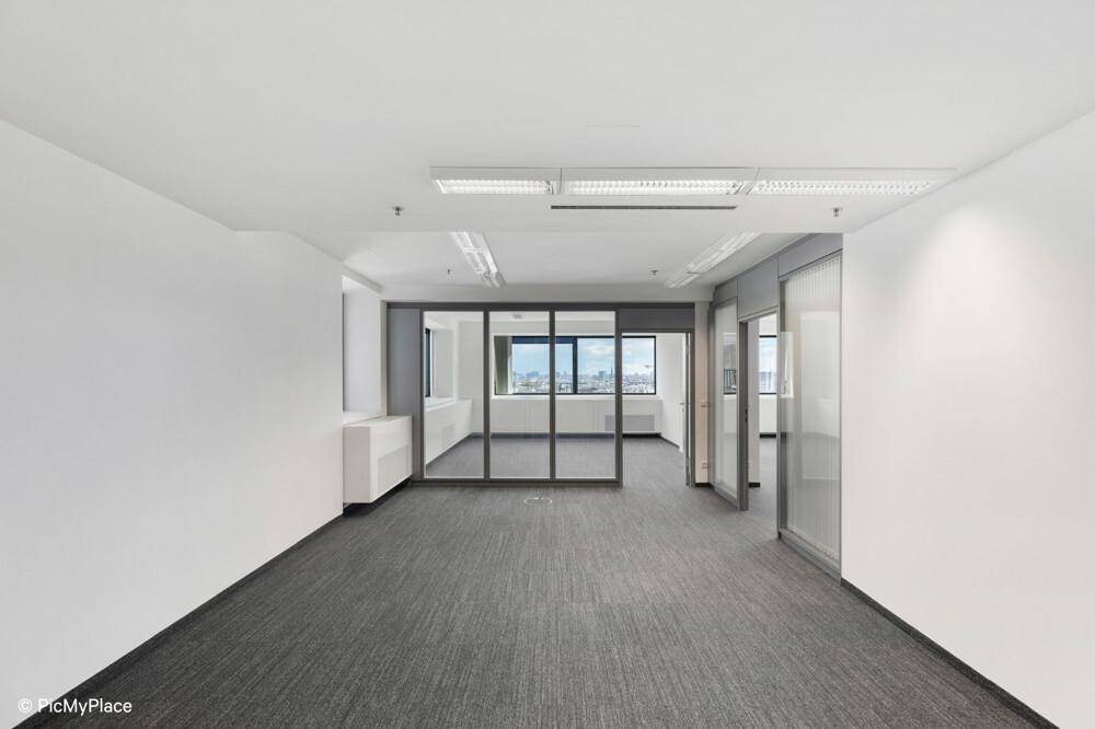 Leerer Büroraum mit Teppichboden, Glaswänden und Blick auf die Stadt.