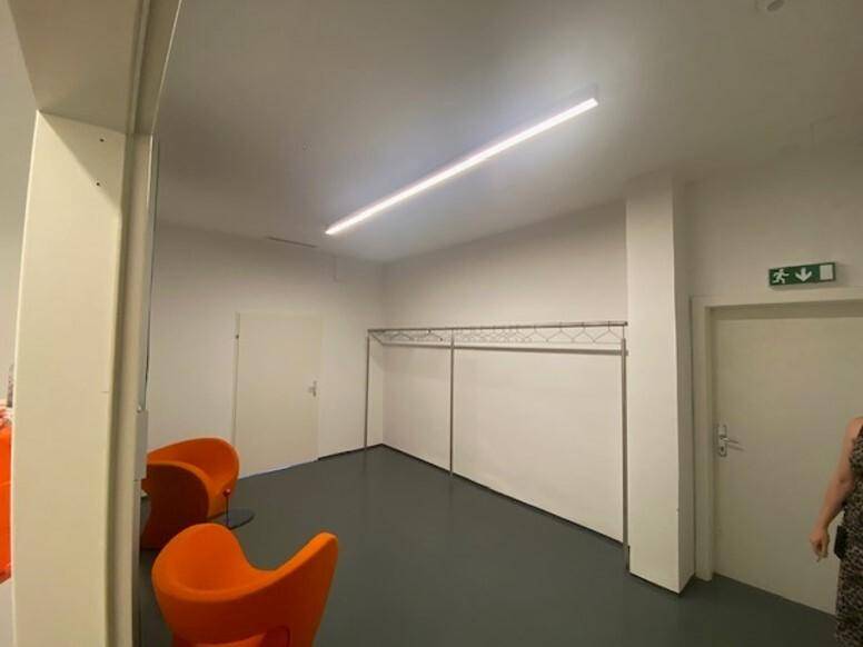 Kleiner Raum mit zwei orangefarbenen Sesseln und einer Kleiderstange an der Wand.