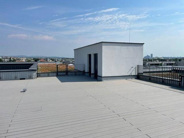 Weitläufige Dachfläche mit einem kleinen Gebäude und Geländer, bietet einen weiten Blick über die Stadt.