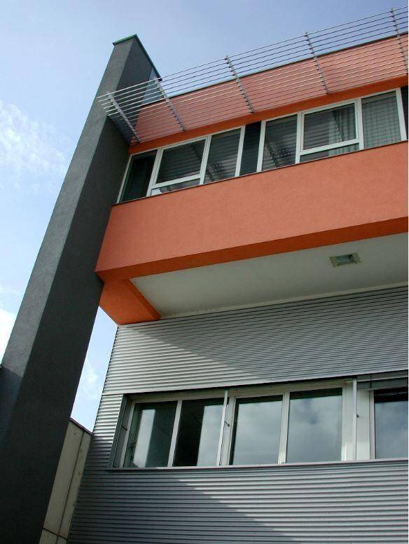 Nahaufnahme der modernen Fassade eines Bürogebäudes mit orangefarbenen Akzenten und Fensterreihen.