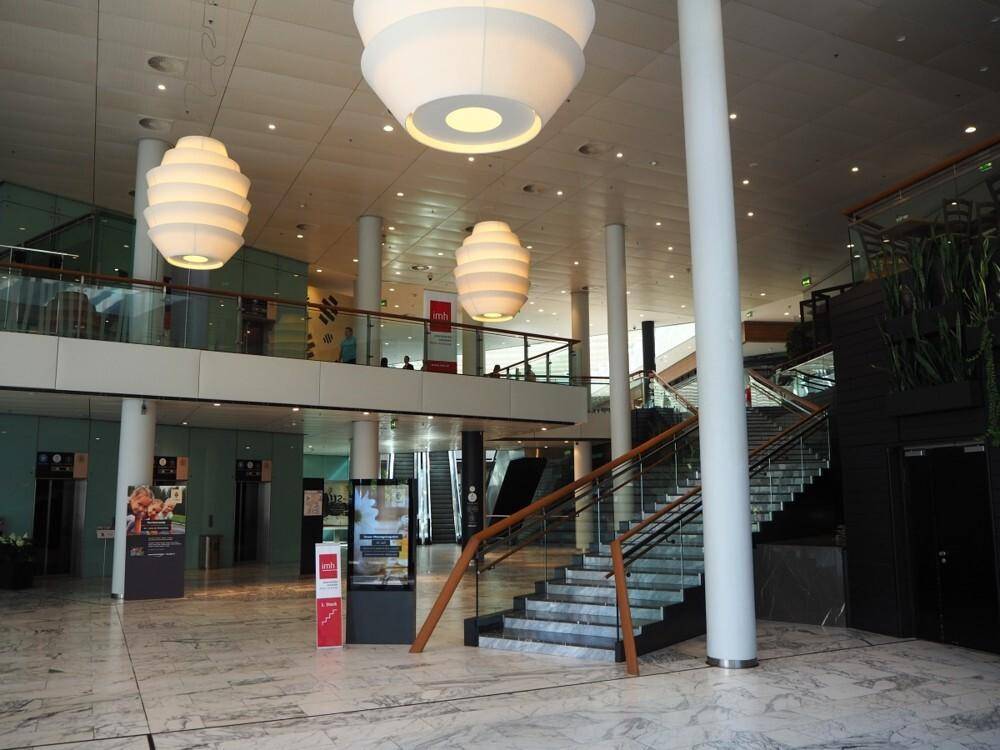 Große, helle Hotellobby mit Marmorboden, hohen Säulen und auffälligen Deckenleuchten.
