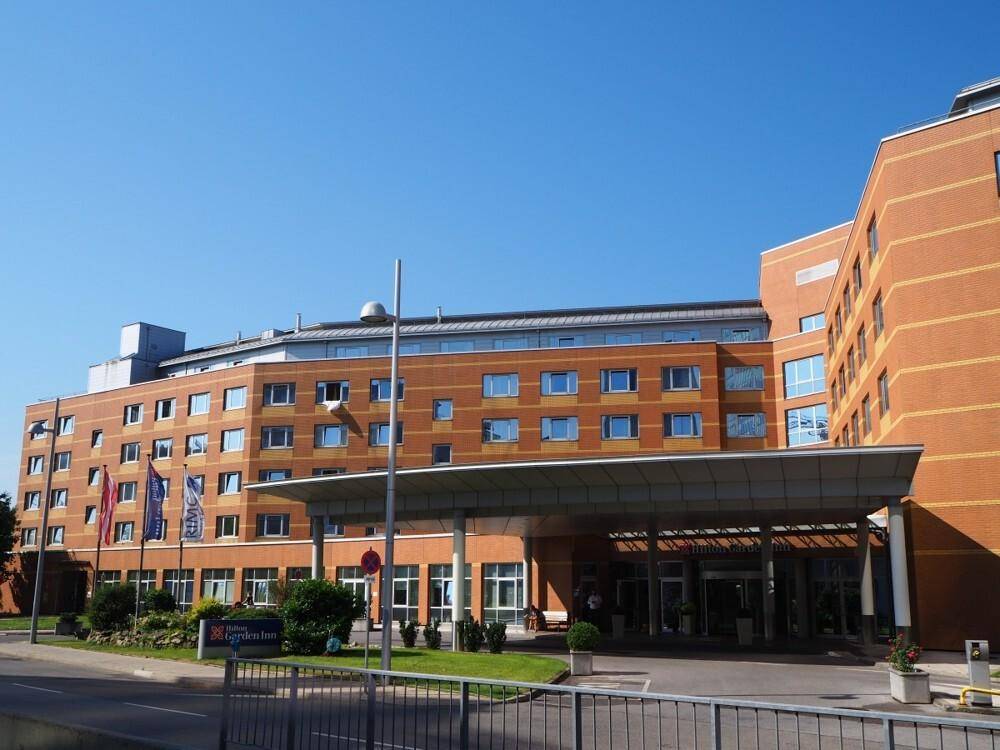 Modernes Hotelgebäude mit brauner Fassade, vielen Fenstern und einem Vordach am Eingang.