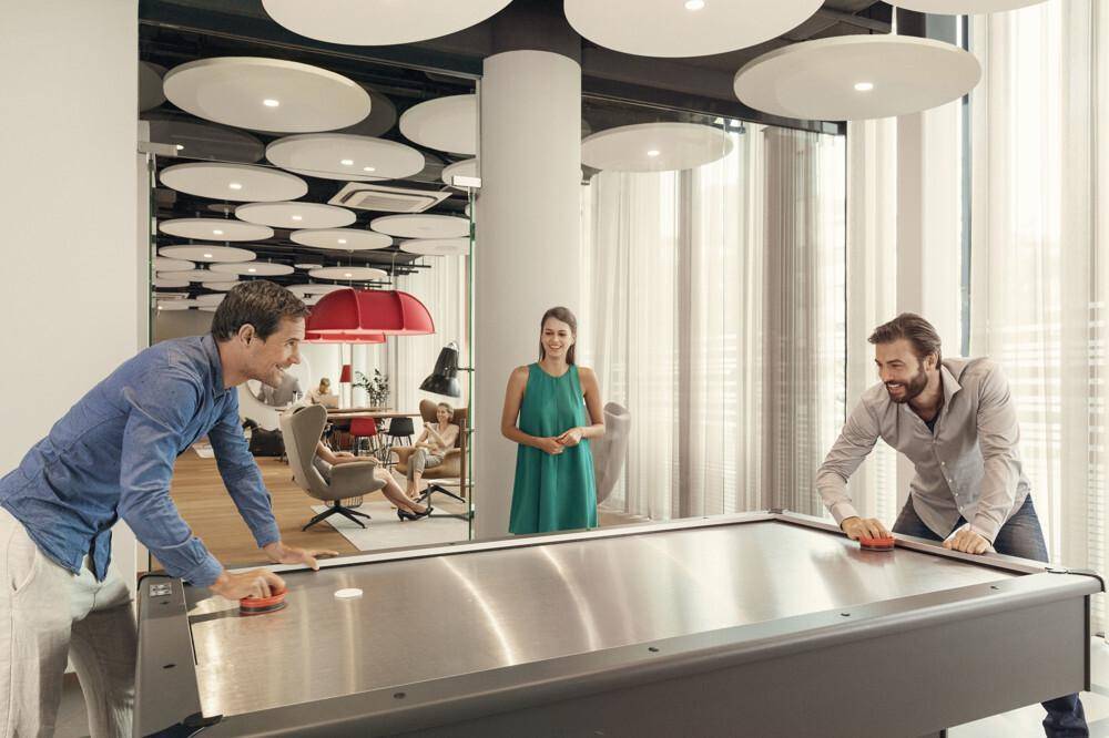 Freizeitbereich mit Airhockey-Tisch und modernen Deckenleuchten, ideal für Pausen und Unterhaltung im Büro.
