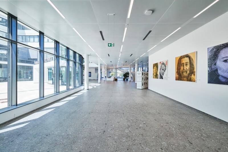 Heller, moderner Flur oder Lobbybereich mit großen Fenstern, Kunstwerken und minimalistischer Beleuchtung.
