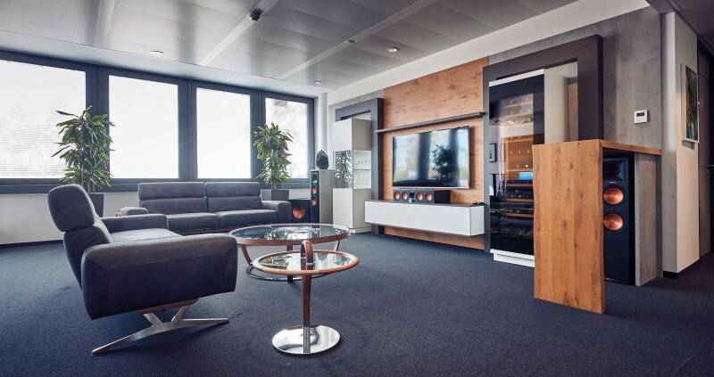 Moderner Wohnbereich mit dunklen Möbeln, großen Fenstern und einer eleganten Medienwand aus Holz.