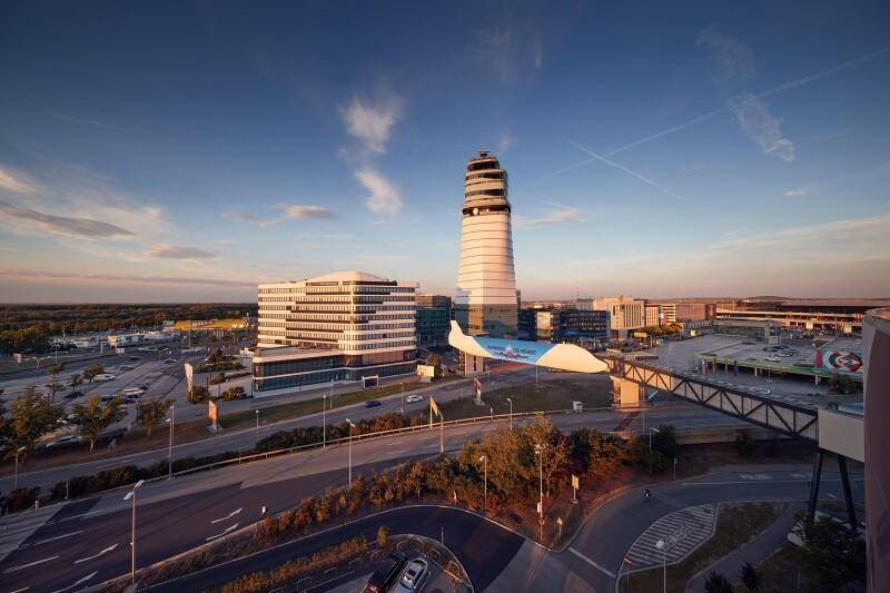 Panoramablick auf das Flughafengelände bei Sonnenuntergang mit Kontrollturm und umliegenden Gebäuden.