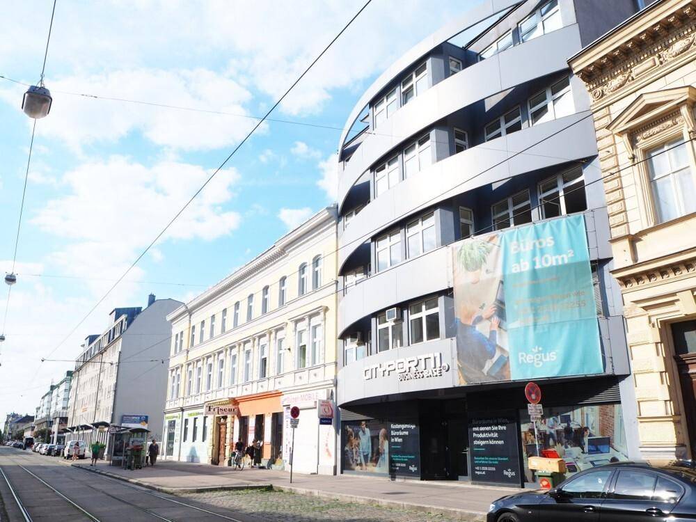 Moderne Geschäftsfassade mit geschwungener Architektur und großen Fenstern an einer belebten Straße in der Stadt.