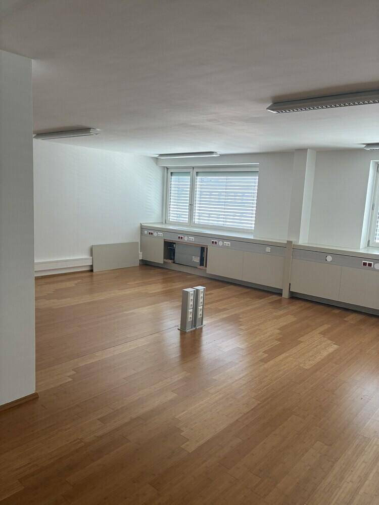 Geräumiger Büroraum mit Holzboden, mehreren Fenstern und einer langen Reihe von Unterschränken.