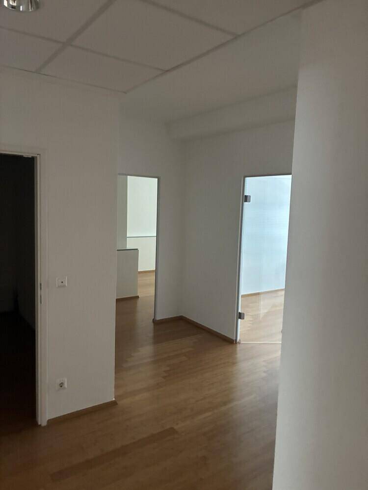 Langer, heller Flur mit Holzboden und mehreren Türen, die zu verschiedenen Büroräumen führen.