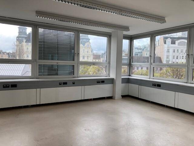 Heller Büroraum mit hellem Boden und großen Fenstern, die einen weiten Stadtblick bieten.