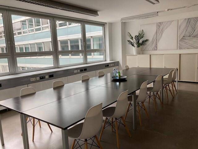 Großer Konferenzraum mit langem Tisch, vielen Stühlen und weitem Blick auf andere Gebäude.