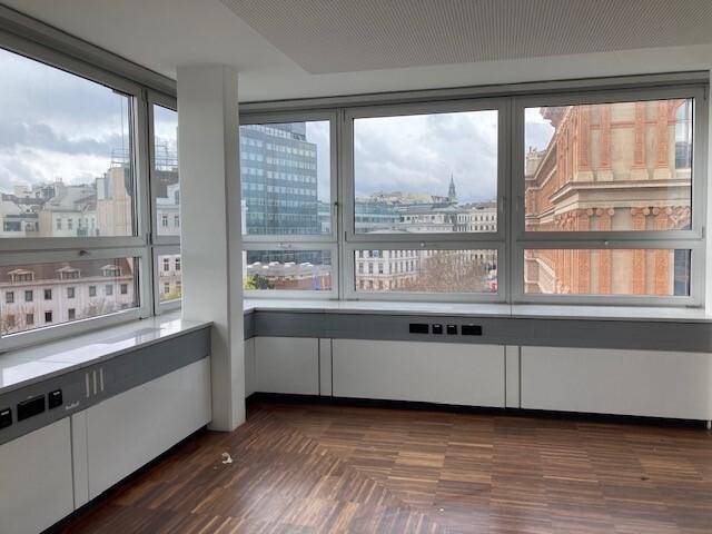 Eckbüroraum mit Holzfußboden und großen Fenstern, die einen weiten Stadtblick ermöglichen.