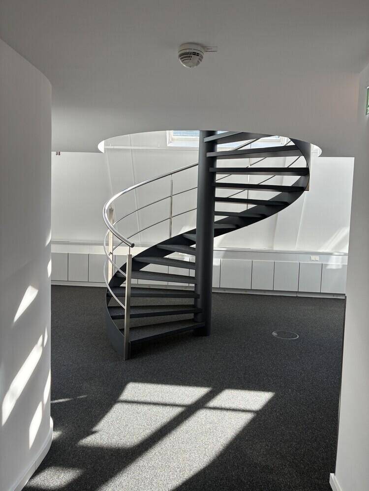 Geräumiger Bürobereich mit einer eleganten Wendeltreppe als zentrales Designelement.