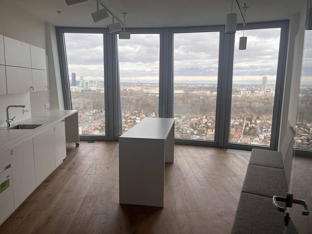 Helle Büroküche mit großen Fenstern, die einen weiten Blick über die Stadt bieten, ausgestattet mit weißen Schränken.