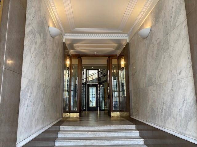 Elegante Eingangshalle mit Marmorwänden, hohen Decken und dekorativer Beleuchtung.