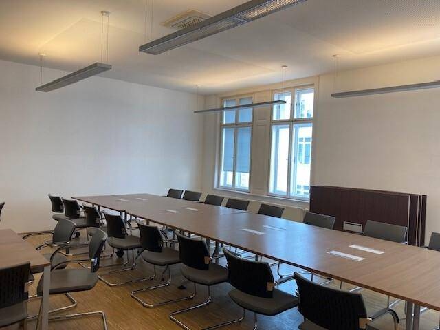 Großer Konferenzraum mit langem Tisch, vielen Stühlen und natürlichem Lichteinfall.