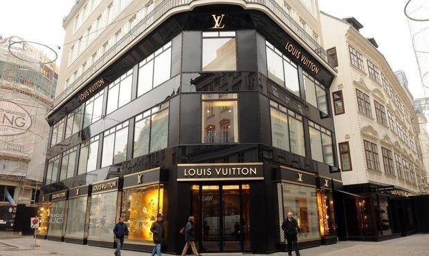 Elegantes Louis Vuitton Geschäftshaus mit glänzender schwarzer Fassade und großen Schaufenstern in einer belebten Stadtstraße.