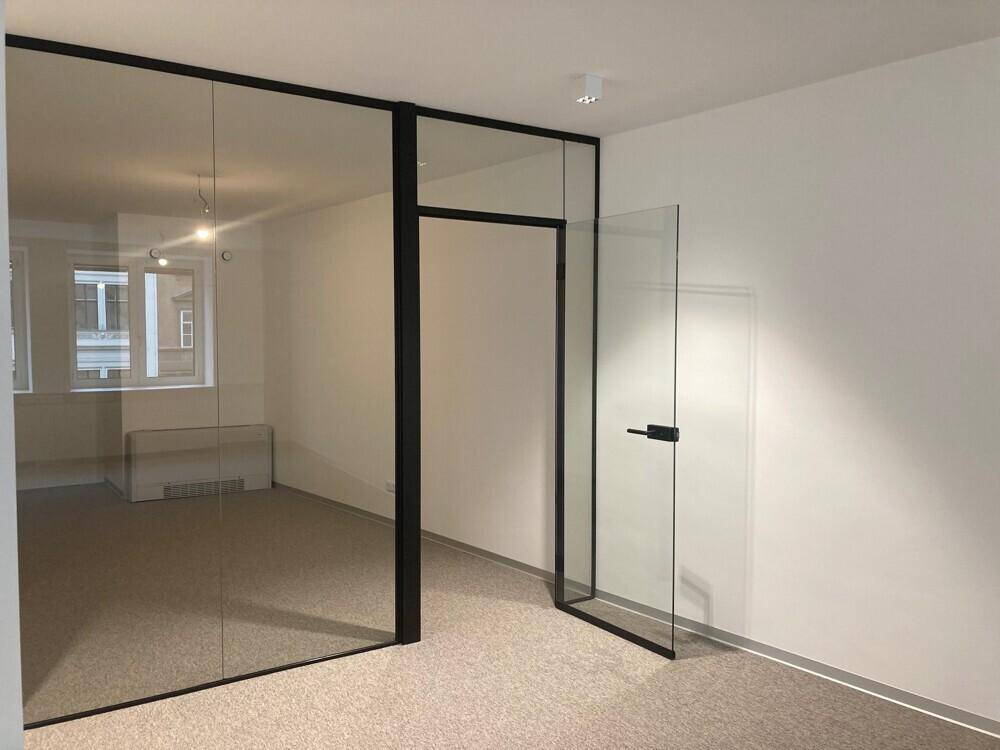 Moderner Büroraum mit Glaswänden und einer Glastür, die eine offene Atmosphäre schafft.