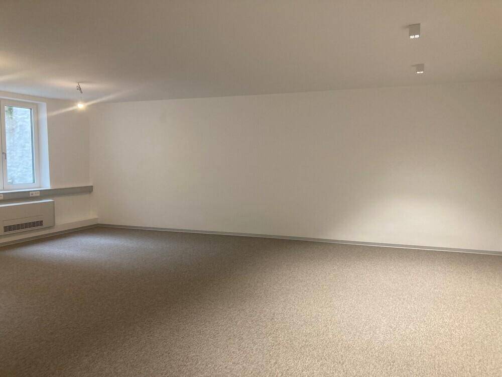 Geräumiger, unmöblierter Büroraum mit Teppichboden und weißen Wänden, bereit zur individuellen Einrichtung.