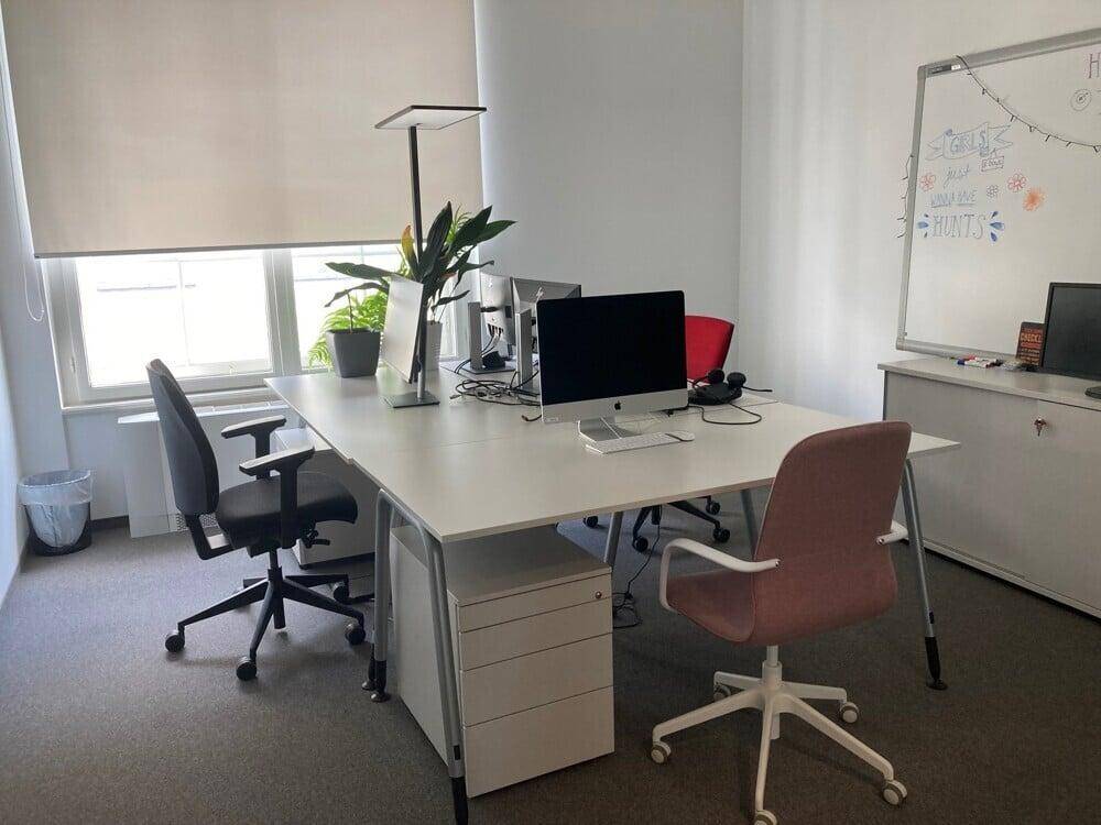 Großraumbüro mit mehreren Arbeitsplätzen, Teppichboden und viel Tageslicht.