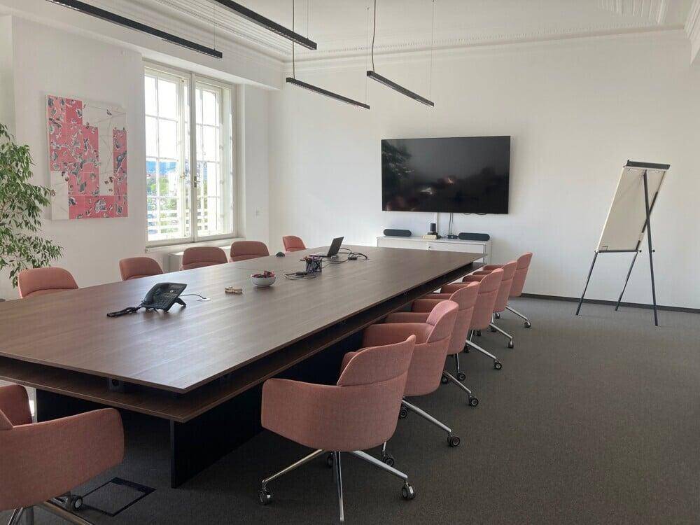 Großer Konferenzraum mit langem Tisch, vielen Stühlen und Blick nach draußen.