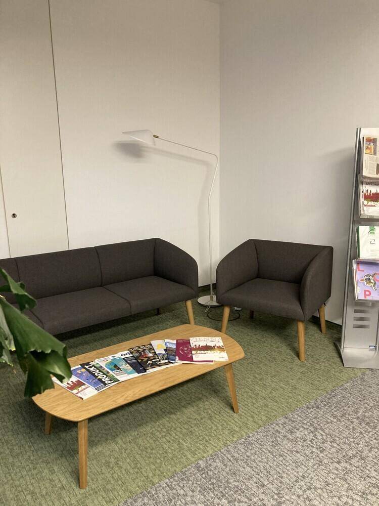 Gemütlicher Loungebereich im Büro mit bequemen Sofas, Couchtisch und Lesematerial.