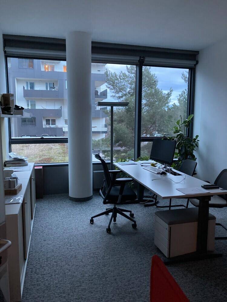 Einzelbüro mit großem Fenster, Blick ins Grüne und moderner Büroeinrichtung.