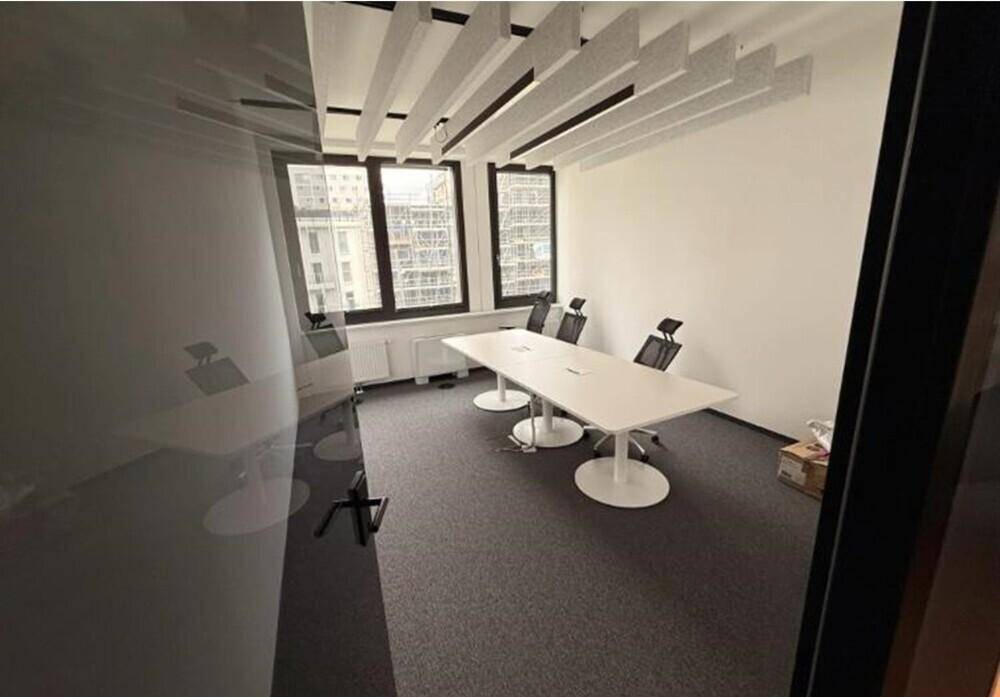 Heller Besprechungsraum mit großem Konferenztisch, ergonomischen Stühlen und schallabsorbierenden Deckenpaneelen.