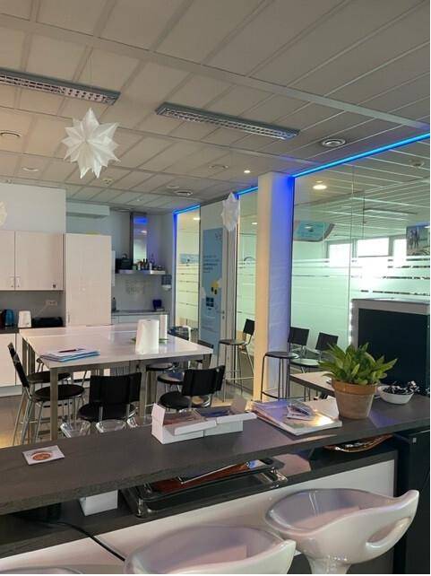 Offener Pausenbereich mit Küchenzeile, Stehtischen und Barhockern in einem modernen Büro.