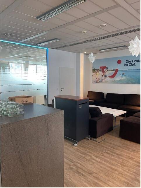 Gemütlicher Loungebereich mit Sofas, Holzboden und dekorativen Elementen in einem Büro.