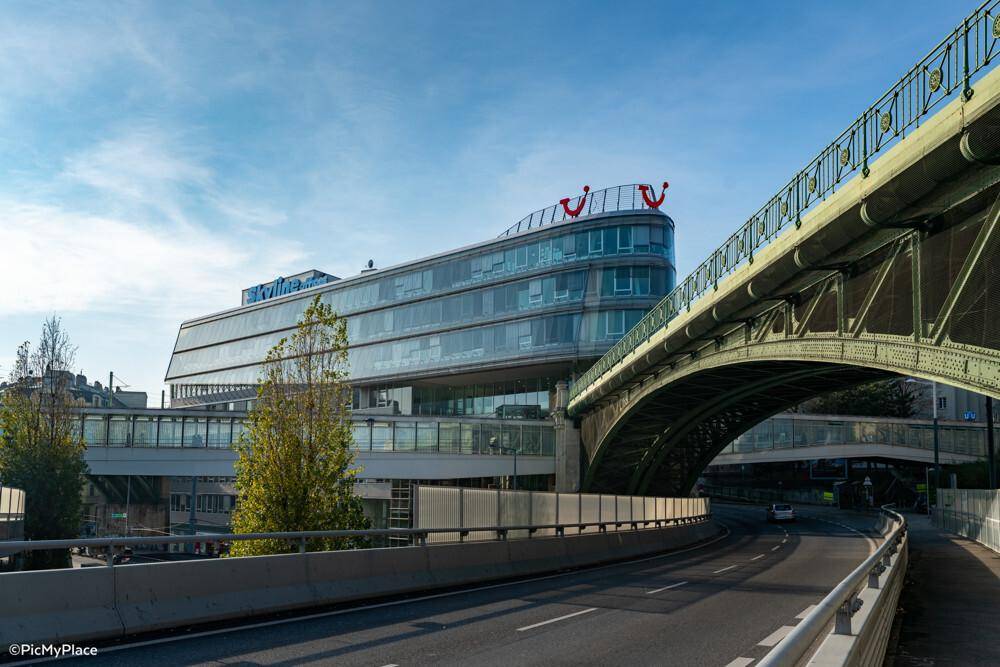 Modernes Bürogebäude mit geschwungener Glasfassade neben einer großen Brücke.