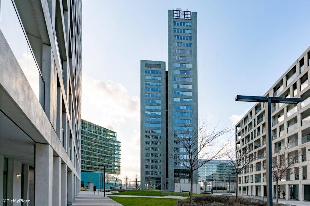 Moderne Hochhäuser mit Glasfassaden und einer gepflegten Grünfläche im Vordergrund.
