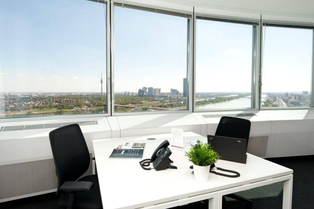 Helles Büro mit Schreibtisch und Stuhl, bietet einen weiten Panoramablick auf die Stadt und den Fluss.