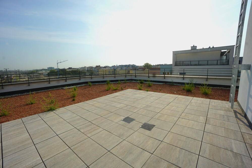 Weitläufige Dachterrasse mit großen Pflasterflächen und Blick auf die umliegende Stadtlandschaft.