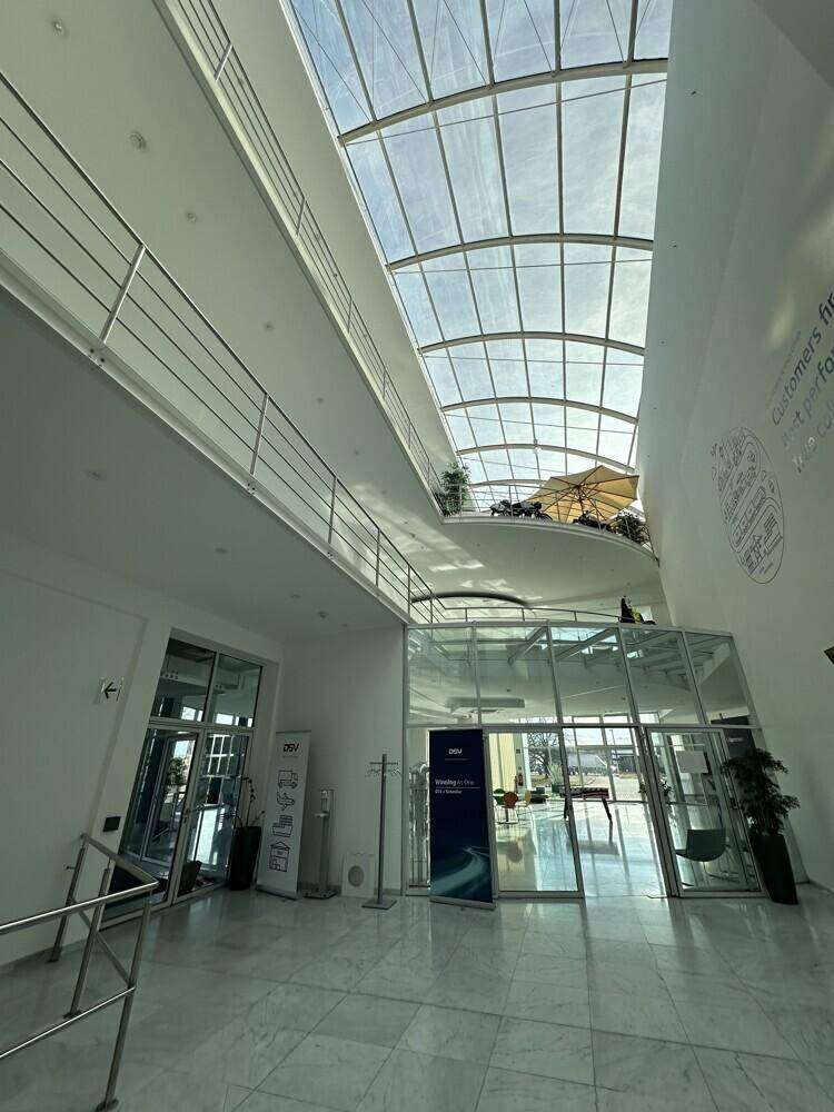 Helle, moderne Lobby mit hoher Glasdecke, Marmorboden und mehreren Ebenen.