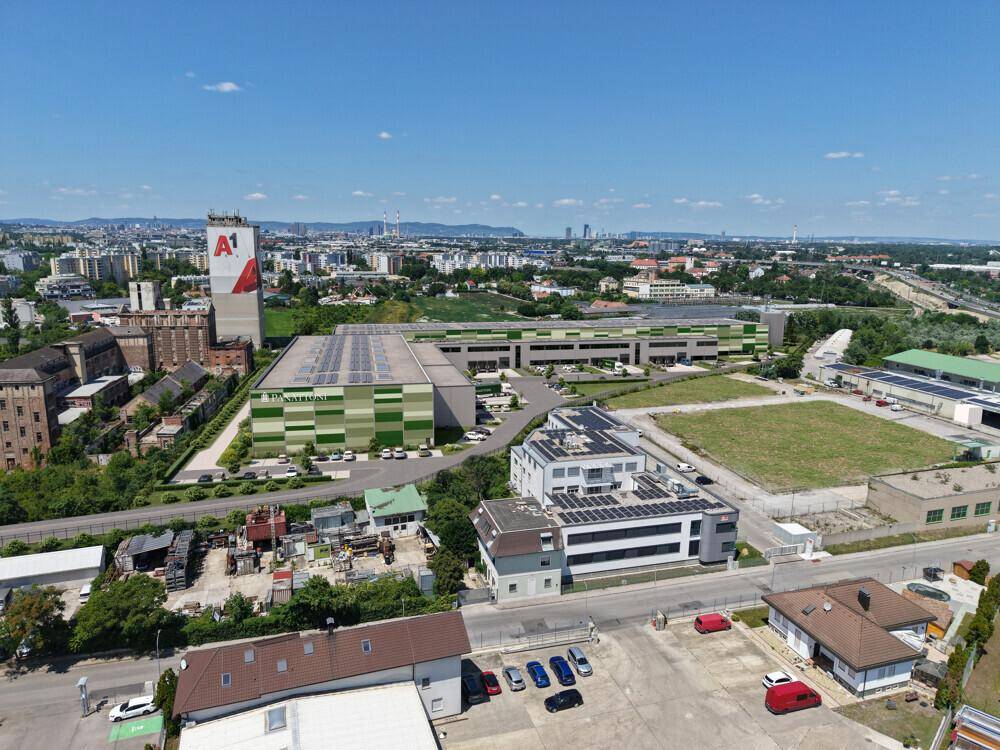 Panoramablick aus der Vogelperspektive auf ein Gewerbegebiet mit mehreren Gebäuden, Solarpaneelen und Parkplätzen.