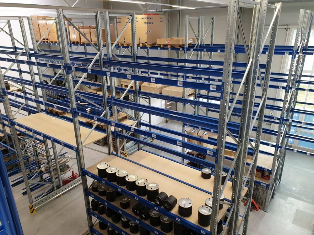 Geräumige Lagerhalle mit hohen Decken und robusten Metallregalen, teilweise mit Waren bestückt.