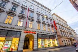 Ansicht eines mehrstöckigen Gebäudes mit beleuchteten Ladenfronten und traditioneller Architektur in der Stadt.