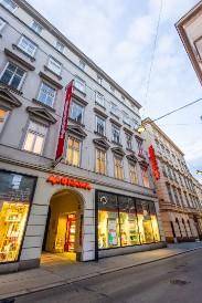 Historisches Gebäude mit Geschäften im Erdgeschoss und klassischer Fassadenarchitektur an einer Stadtstraße.