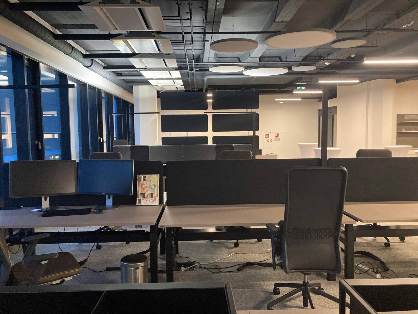 Großraumbüro mit mehreren Arbeitsplätzen, Monitoren und abgehängter Decke, die eine funktionale Umgebung schafft.