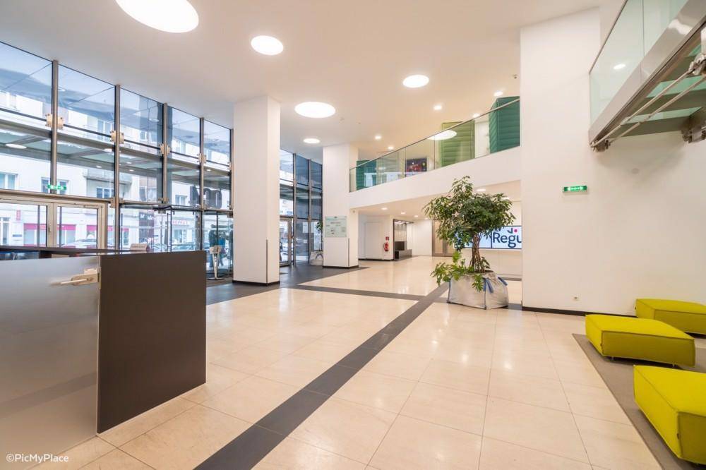 Geräumige und helle Lobby mit Rezeption, Fliesenboden und modernen Sitzgelegenheiten in leuchtendem Gelb.