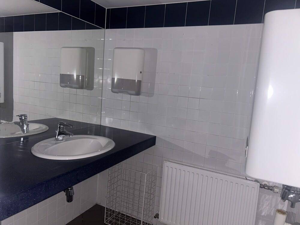 Waschraum mit zwei Waschbecken, großem Spiegel und Heizkörper unter der Ablagefläche.
