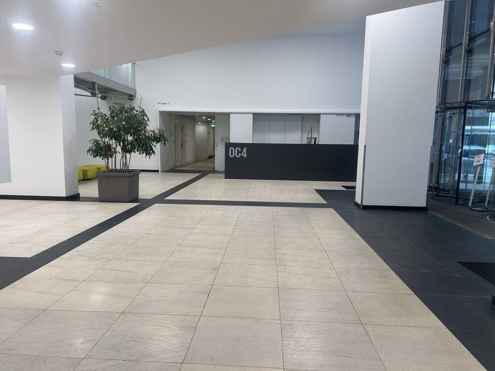 Geräumige Lobby mit Rezeption, Fliesenboden und Zugang zu den oberen Etagen über einen Aufzug.
